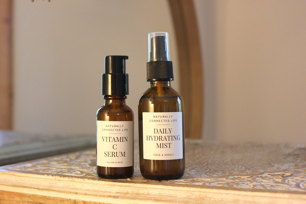 Vitamin C Serum and Daily Hydrating Mist in amber glass bottles on a wooden table